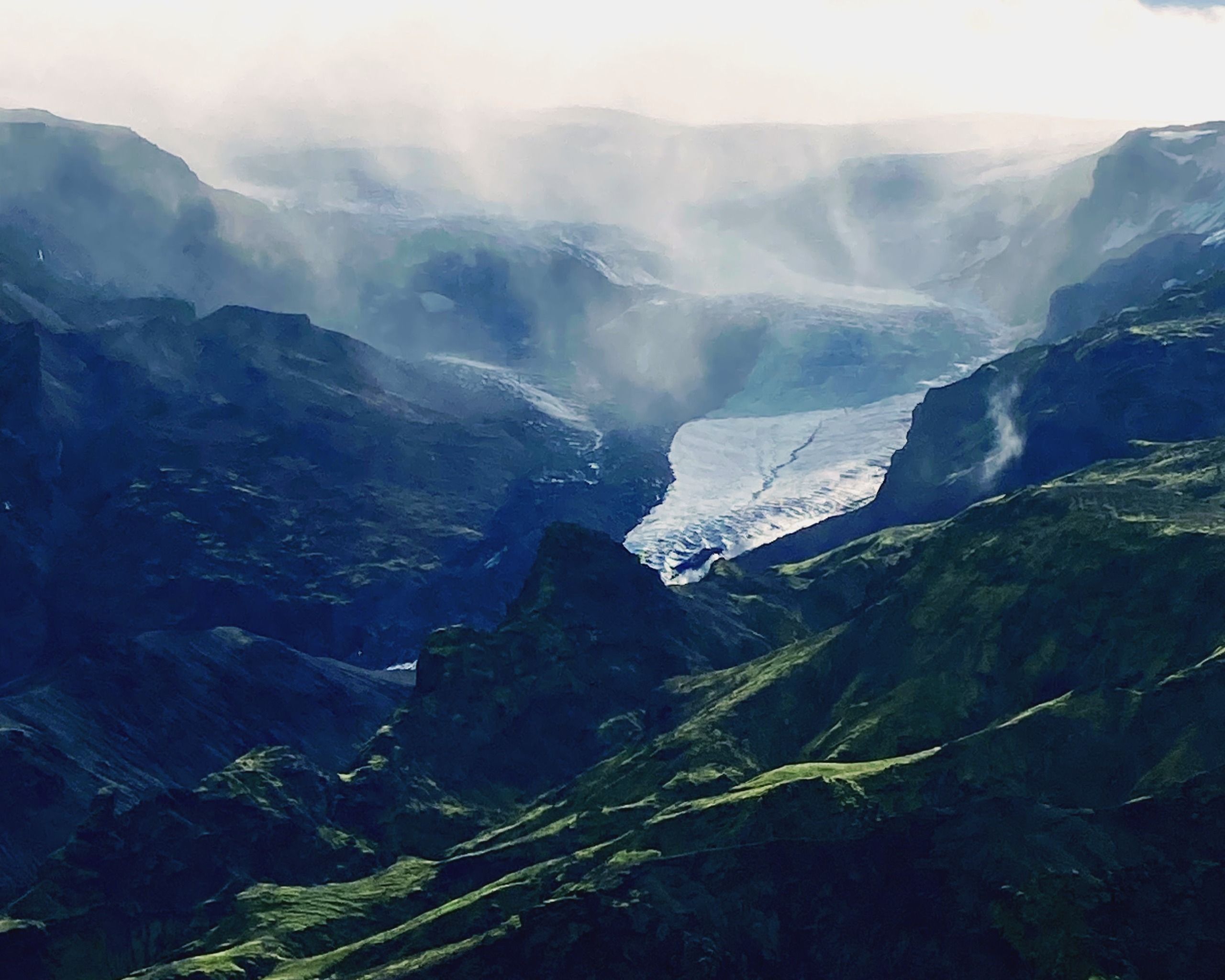 Misty green gorge with a glacial river winding far below in the vast Icelandic highlands